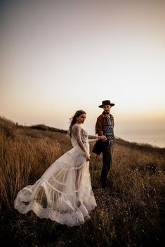 a man and woman standing on top of a grass covered field next to each other