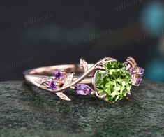 a green ring with leaves and amethysts on it sitting on top of a rock