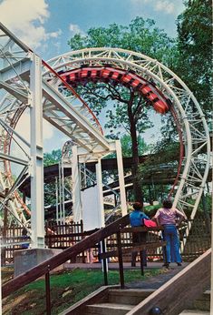 two people are standing at the top of a roller coaster ride in an amusement park