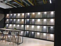 a room with several tables and stools in front of a wall that has lights on it