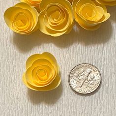 small yellow paper flowers sitting next to a penny