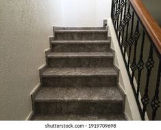 an image of stairs going up to the top floor in a house or apartment with white walls and black iron railings