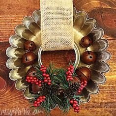 a metal wreath with bells and berries hanging on a wooden wall next to a burlock