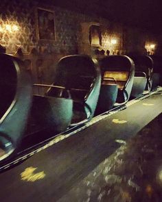 empty chairs are lined up along the wall in a dark room with chandeliers hanging from the ceiling