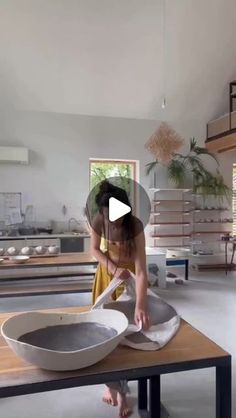 a woman is using a large bowl on top of a table