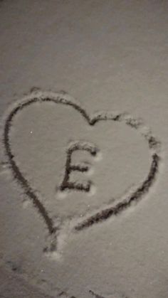 a heart drawn in the snow with letters e and f on it's side