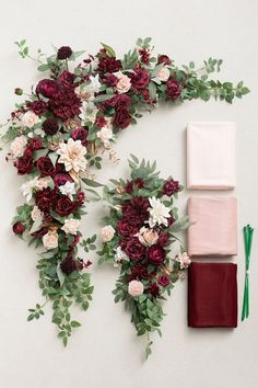 an arrangement of flowers and greenery laid out on a white surface next to each other