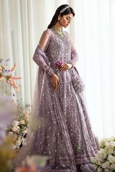 a woman standing in front of a window wearing a purple dress and tiara with flowers on it