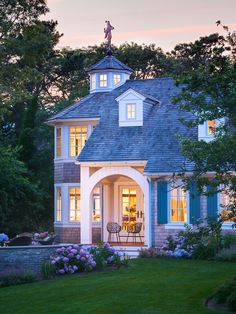 a house with blue shutters and white trim on the front door, surrounded by lush green grass