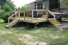 a wooden deck next to an rv parked in the grass