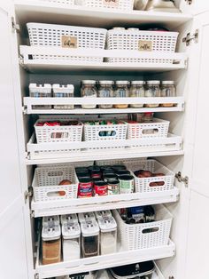 an organized pantry with white bins and baskets