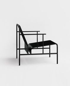 a black chair sitting on top of a white floor next to a metal frame structure