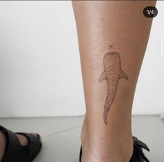 a small tattoo on the leg of a woman's foot with a whale tail