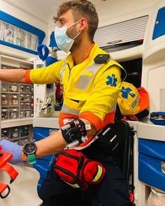 a man in an orange and yellow uniform is working on some electrical equipment while wearing a face mask