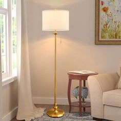 a living room with a white couch and a gold floor lamp in it's corner