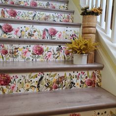 some flowers are sitting on the stairs next to a potted plant and wallpaper