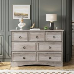 a bedroom with a dresser, lamp and pictures on the wall