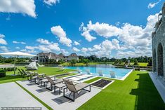 an outdoor dining area next to a swimming pool with lounge chairs and umbrellas on the grass