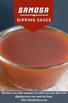 a glass bowl filled with sauce sitting on top of a wooden table next to a red sign