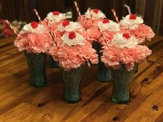 several vases with flowers and candy canes in them sitting on a wooden table