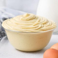 a bowl filled with whipped cream next to eggs