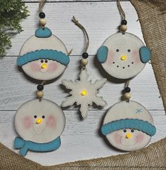 four snowman ornaments hanging on a wooden board