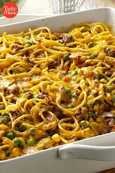 a casserole dish with noodles, meat and peas in it on a table