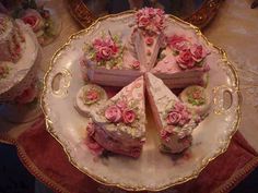 there are several pieces of cake on the plate with pink flowers and roses around it