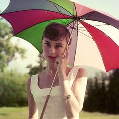 a woman holding an umbrella while standing in the grass