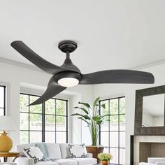 a living room with a white couch and a ceiling fan in front of a fireplace