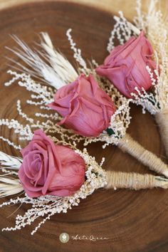 two pink roses are placed next to each other on a piece of wood with dry grass