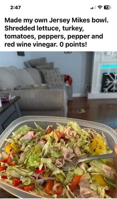 a plastic container filled with salad next to a couch