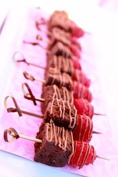 a row of chocolate and raspberry skewers sitting on top of a table