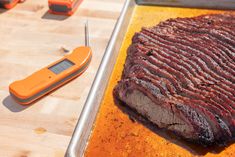 a piece of meat on a tray with a digital thermometer next to it