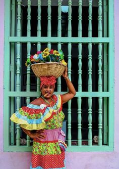 a woman with a basket on her head standing in front of a window