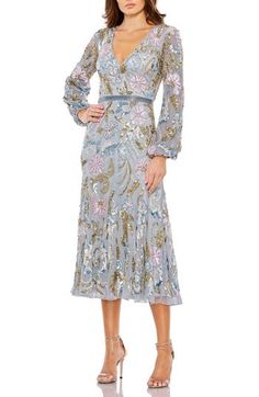 a woman is wearing a dress with long sleeves and a floral pattern on the front