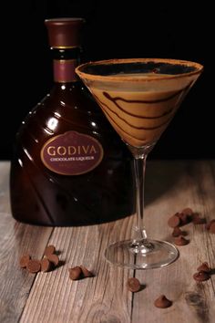 a glass filled with liquid sitting next to a bottle on top of a wooden table