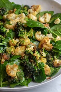 a white bowl filled with spinach and cauliflower