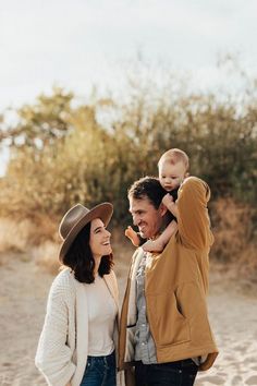 a man and woman holding a baby on their shoulders