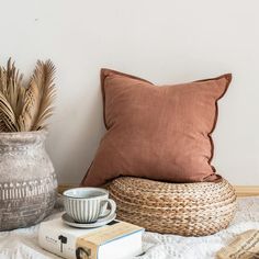 a coffee cup sitting on top of a bed next to a basket and bookcase