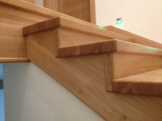 a close up view of some stairs with wood handrails and green light at the bottom