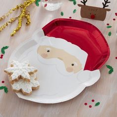 a paper plate with santa clause and cookies on it next to other christmas decoration items