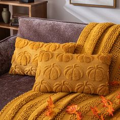 a couch with two yellow pillows on top of it and an orange blanket next to it