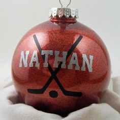 a red ornament with the word nathan written on it and hockey sticks sticking out of it