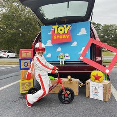 a man riding a bike next to a toy story truck with boxes on the back