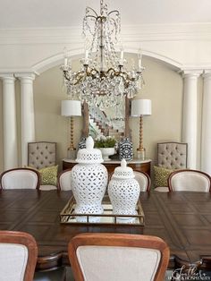 a dining room table with white vases and chandelier