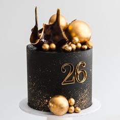 a black and gold cake with decorations on top