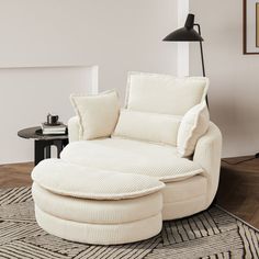 a living room with a large white chair and ottoman on the floor next to a lamp