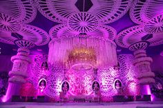 an elaborate chandelier is hanging from the ceiling in front of purple lights and decorations