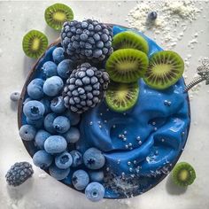 a blue dessert topped with kiwis, berries and grapes